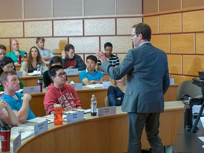 Photo of a professor teaching at the front of a lecture hall