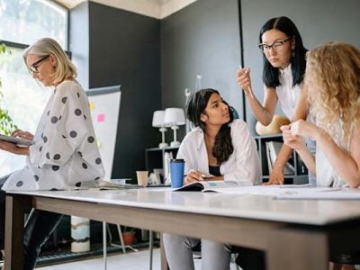 Office setting with four women collaborating.