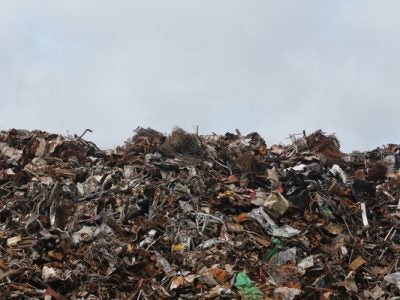A trash heap is piled high against a clear sky