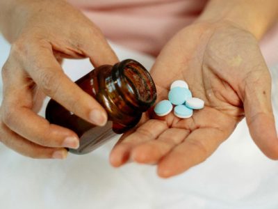 A pair of hands with a prescription bottle and pills