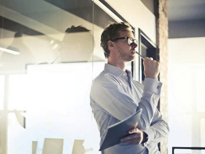 A male professional in an office environment thinking