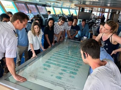 Photo of students looking over ship blueprints and maps