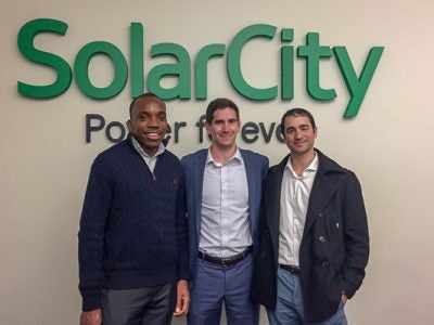 Photo of Mark and two other male students standing in front of a SolarCity sign