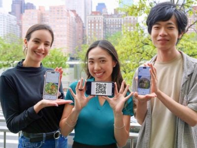 Image of master’s students Alexandra Taic (left), Selina Li and Zach Zhong, all principals of Gymii.ai, a new nutrition tracking app, hold up the app and a recent QR code.