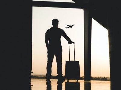 person with suitcase watching a plane take off