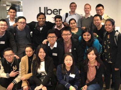 A group of students stands in front an Uber sign