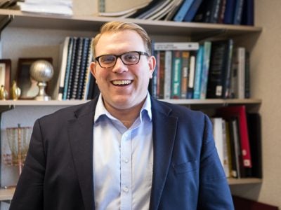 Photo of Vince Slaugh standing in front of a bookshelf smiling