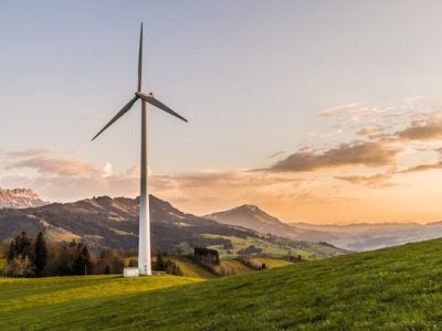 A wind turbine stands amid rolling hills.
