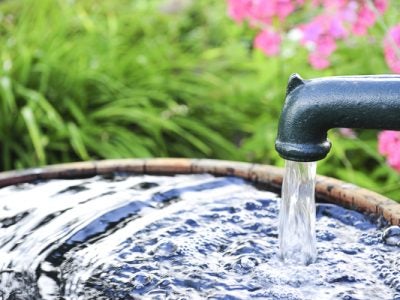 Water pump filling a bucket in a garden