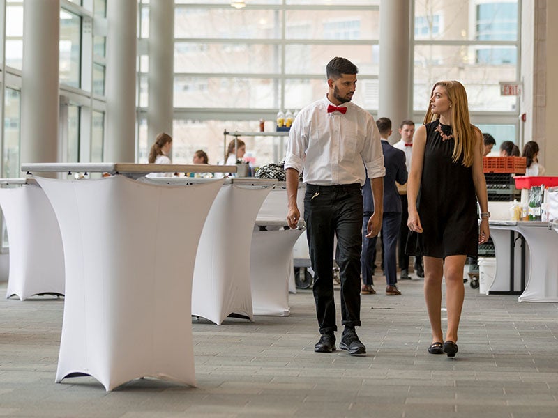 Two students walking and talking while preparing for an HEC event.