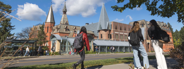 sage hall panoramic with students on sidewalk in fall.
