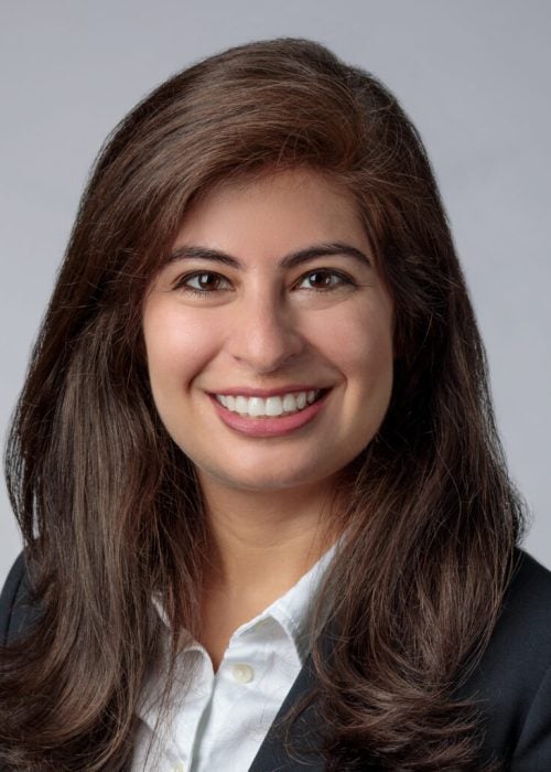 Business headshot of a young woman in business formal attire against a gray backdrop