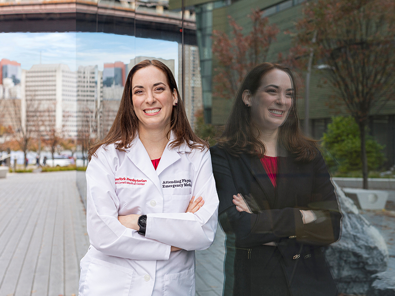 woman standing against glass in a suit and white coat