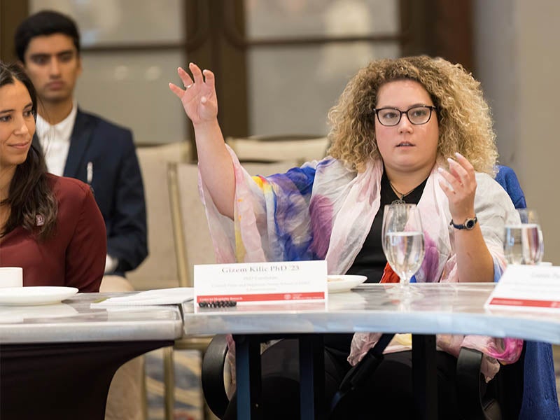 A young woman raises her hand in a classroom as part of studying in the Cornell Nolan School's M.S. or Ph.D. program.