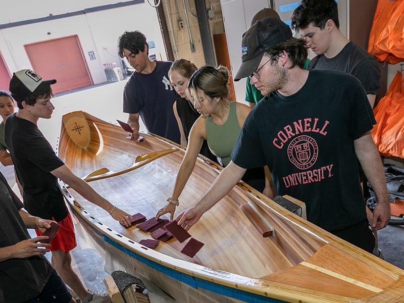 Students complete a fine sanding of a finished canoe to be donated as part of the Grand Challenges program.