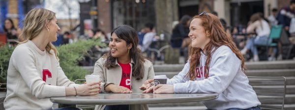 Three students sitting at outside table in Collegetown