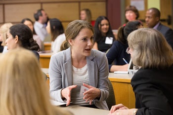 Two women discuss a topic in a lecture hall