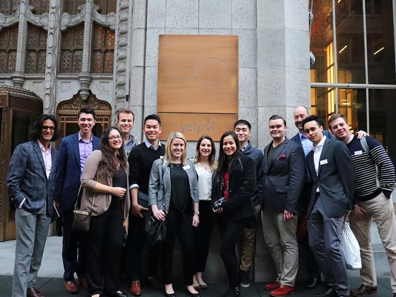 A group of students posing in a group in front of Yelp in San Francisco during a career trek.