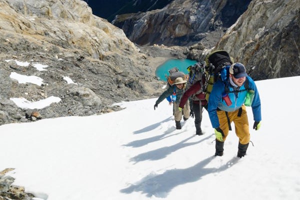 Four Cornell MBA students in winter hiking gear and large backpacks climb a snow-covered mountain as part of an excursion for their Cornell MBA student experience