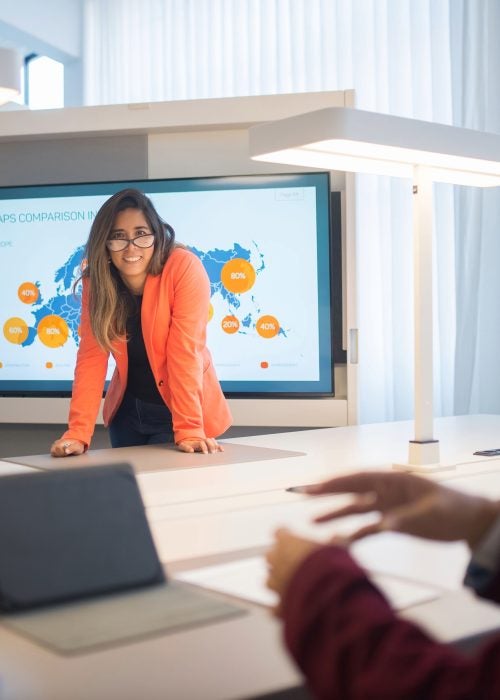 Corporate team engaged in a lively discussion around a digital presentation, fostering collaboration and innovation.