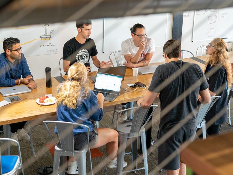 People sitting around a table with laptops.
