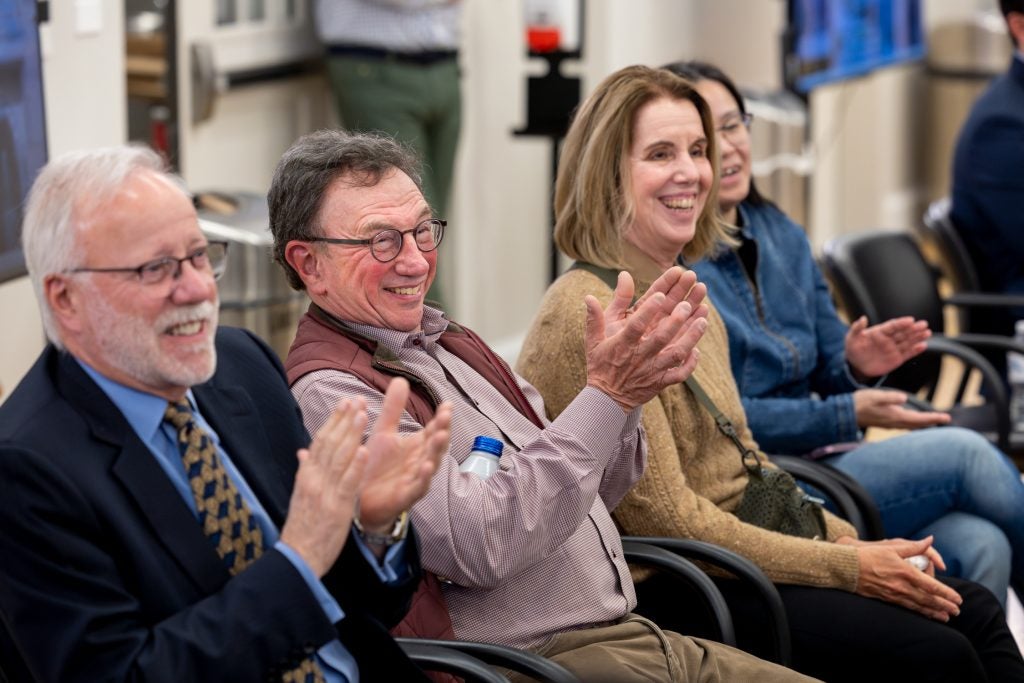 People sitting and clapping with big smiles on their faces.