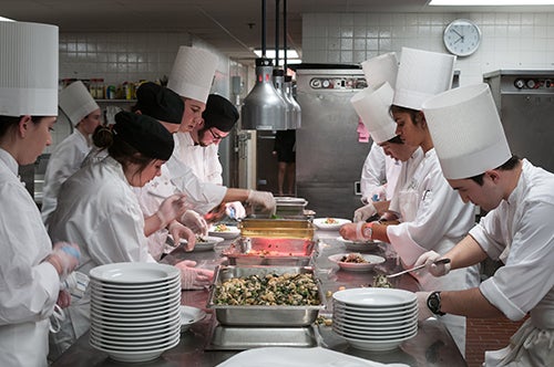 HEC student chefs learning together in a kitchen.