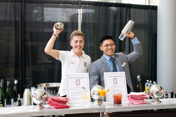 Two students shaking drinks behind a bar at HEC.