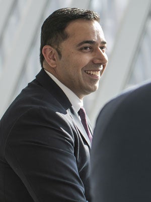 A male business student in a suit smiling.