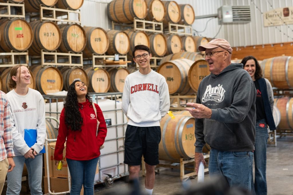 Dyson students laughing while listening to the owner of Treleaven Winery while on an on-site visit of their barrel room.