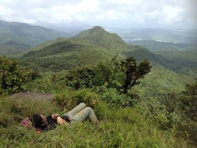 A person rests in the grass looking at a mountain.