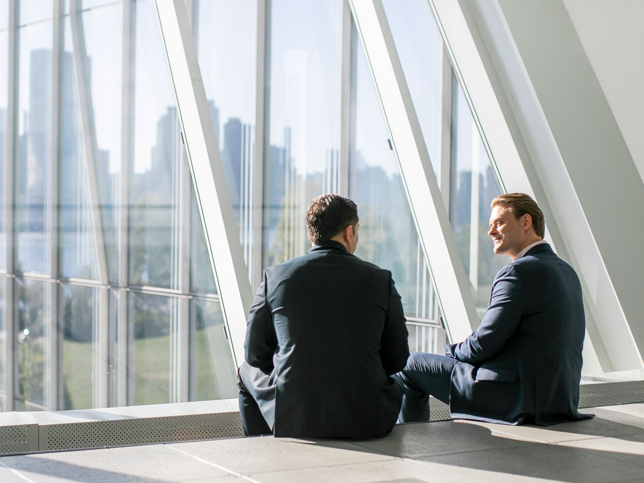 Two male business professionals talking with the NYC skyline in the back.