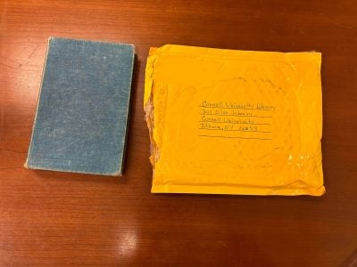 Photo of book by John Cowper Powys next to mailing envelope addressed to Cornell University Library.