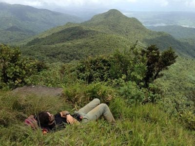 A person rests in the grass looking at a mountain.