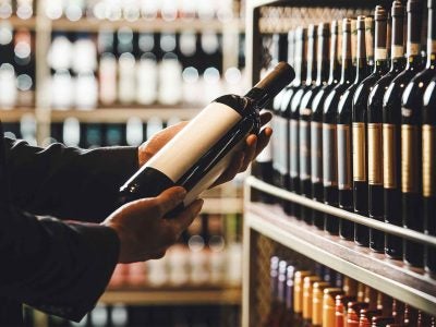 A person examines the label on a wine bottle.
