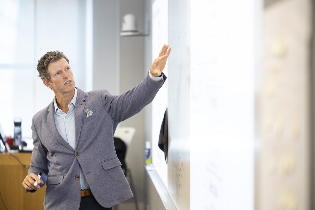 Jess Cisco '12, MBA '17 stands in front of a whiteboard gesturing at the board.