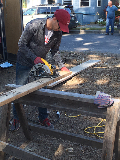 Photo of Matt Muskin sawing a piece of wood while working on a Habitat for Humanity project