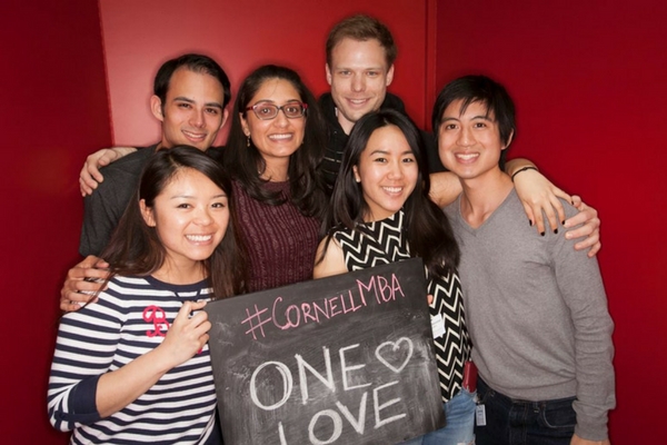 Photo of Johnson MBA students in a photo booth holding a chalkboard sign that says