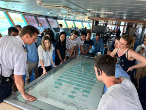 Students looking over a detailed drawing/map of the cruise ship