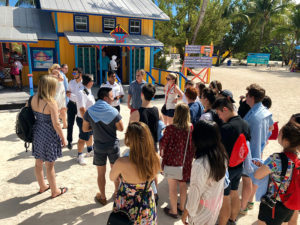 Photo of students gathered on a beach in front of a store