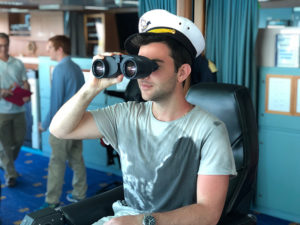 Photo of a student sitting in the captains chair with binoculars