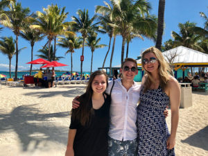 Photo of three students in front of palm trees