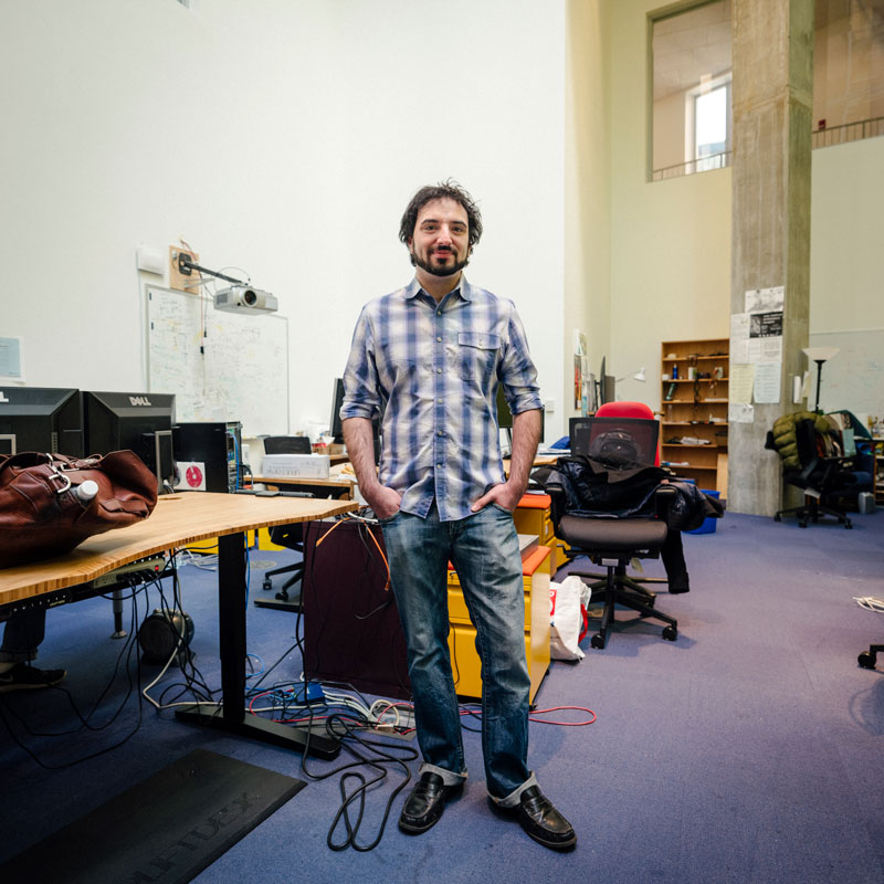 Photo of Greg standing in the center of his lab, surrounded by tables