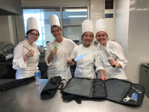 Photo of students dressed in culinary attire in a kitchen