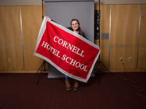 Photo of Marissa holding a banner that read Cornell Hotel School