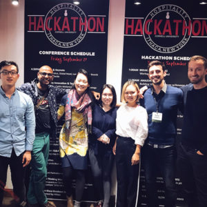 Photo of Nathan and teammates in from of Hackathon banners