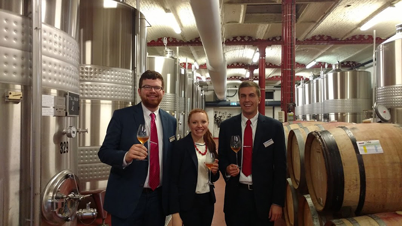 Photo of students posing in front of wine barrels