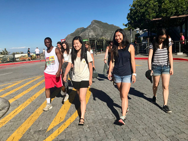 Photo of students walking down the road with mountains in the background