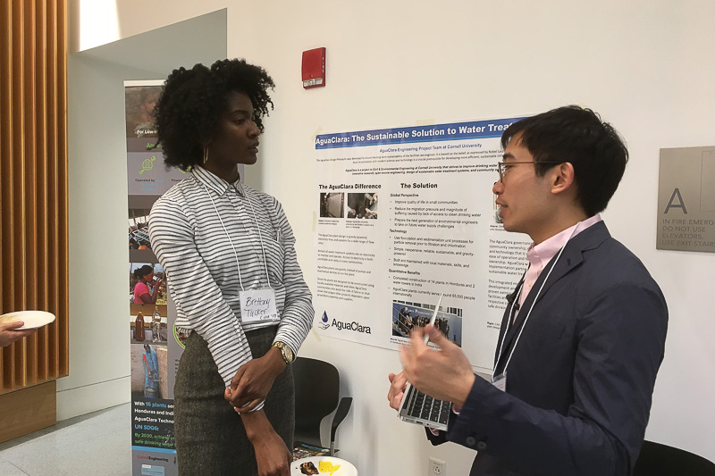 Photo of a student discussing his poster project with a visitor