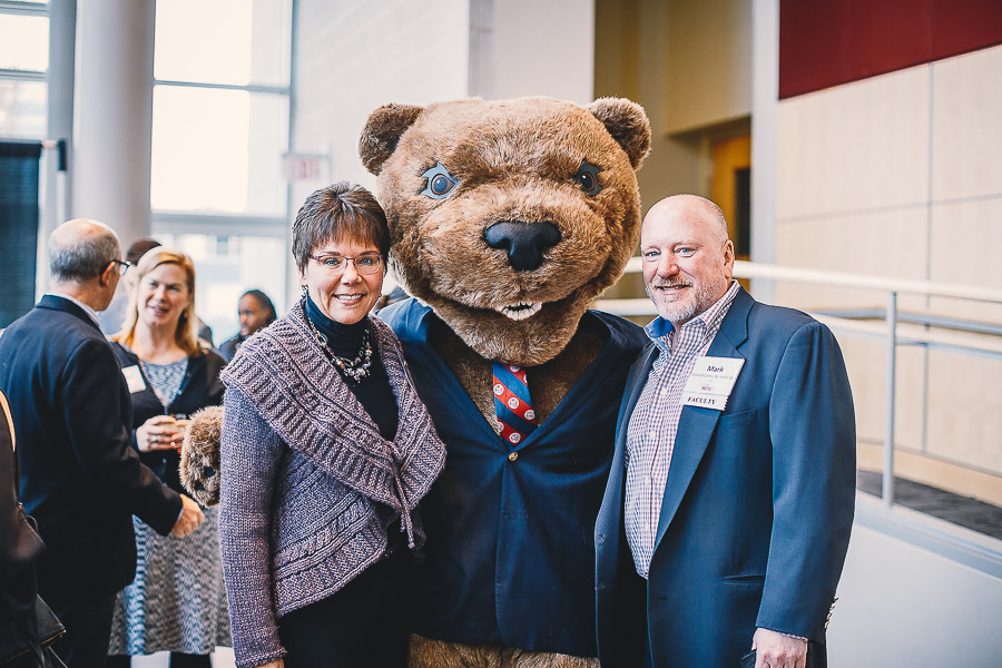 Photo of two visitors standing with Touchdown the mascot